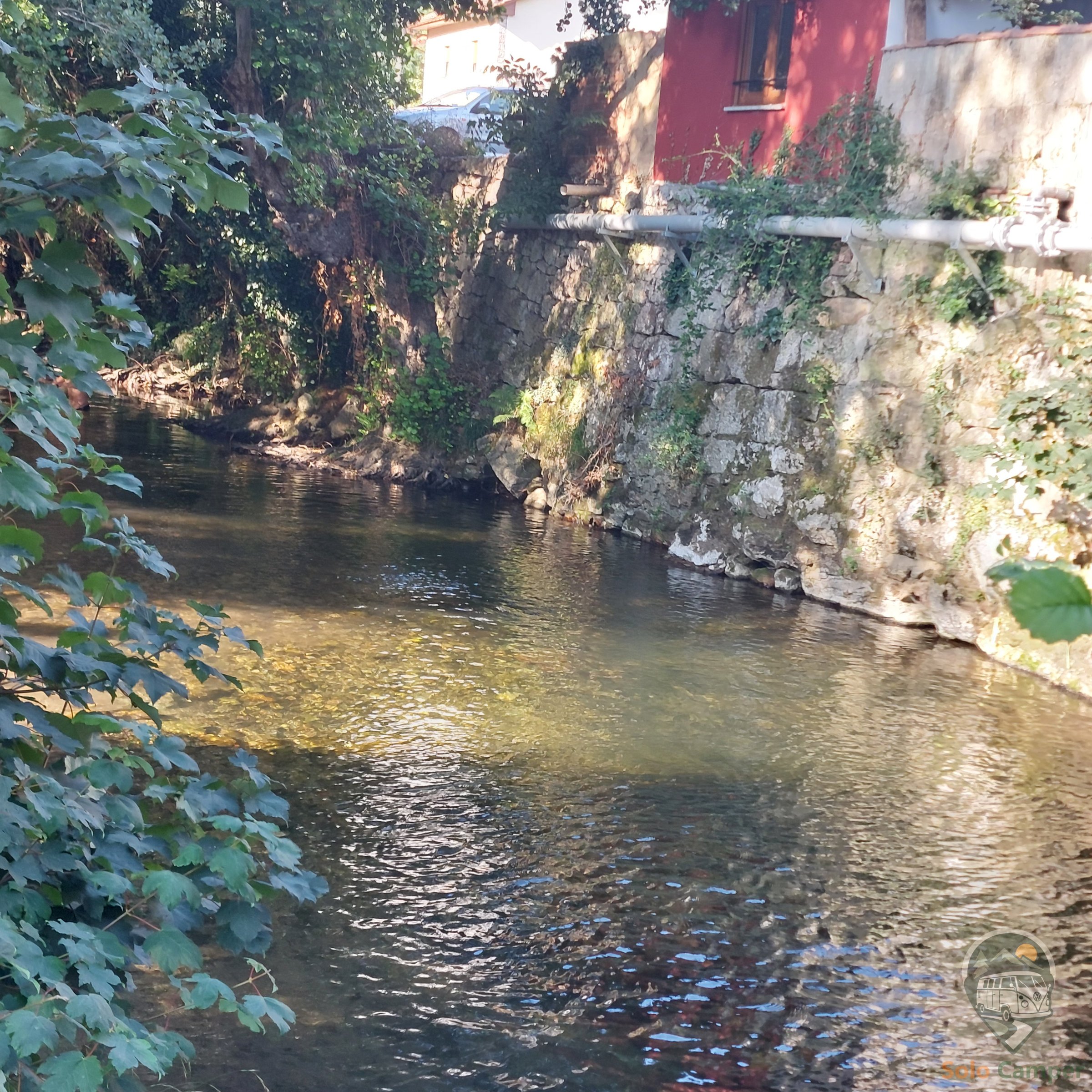 Río junto al área, con casas tradicionales al fondo